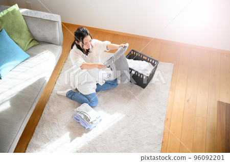 A woman folding towels and other laundry Smile Wide-angle bird's-eye view A woman folding towels and other laundry Smile Wide-angle bird's-eye view 96092201