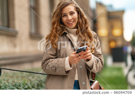 Young woman using mobile device standing in the city Young woman using mobile device standing in the city 96094709