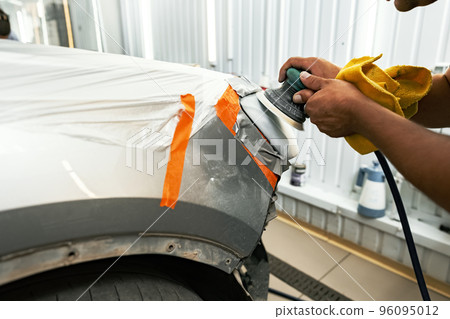 Close up of car cleaner polishing headlight with polish machine Close up of car cleaner polishing headlight with polish machine 96095012