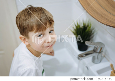 cute 6 years old boy washing his face over the sink in bathroom. Image with selective focus 96095250