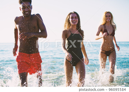 Group of friends run in the sea. Concept of summertime 96095584
