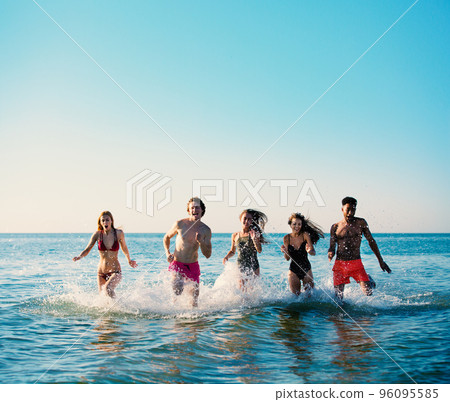 Group of friends run in the sea. Concept of summertime 96095585