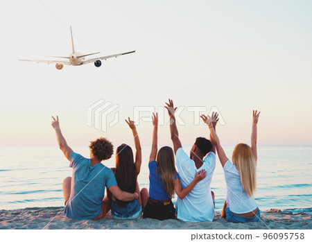 Group of friends having fun on the beach with flying aircraft Group of friends having fun on the beach with flying aircraft 96095758