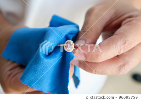 Jeweller hand polishing and cleaning jewelry diamond ring with micro fiber fabric Jeweller hand polishing and cleaning jewelry diamond ring with micro fiber fabric 96095759