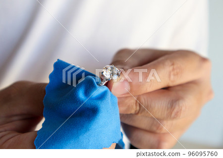 Jeweller hand polishing and cleaning jewelry diamond ring with micro fiber fabric 96095760