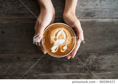Latte art coffee with swan shape in coffee cup holding by hand 96096425
