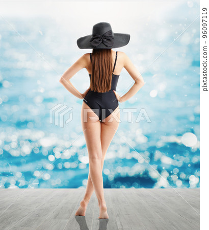 Woman in elegant black hat and swimsuit looks at sea Woman in elegant black hat and swimsuit looks at sea 96097119