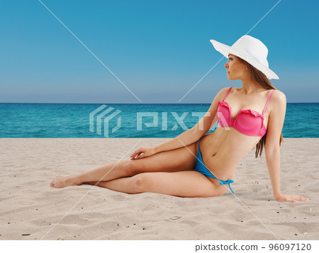 Girl in bikini sunbathing on beach 96097120