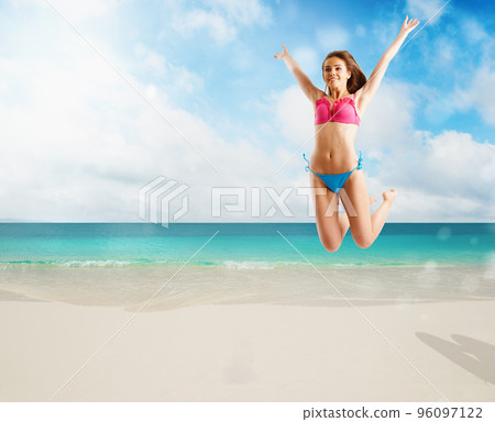 Woman in bikini swimsuit jumping from joy on tropical beach 96097122