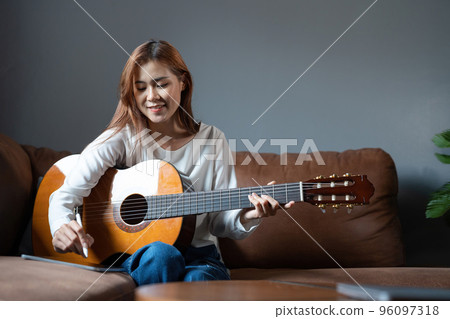 Image of happy beautiful woman playing guitar and composing song. 96097318
