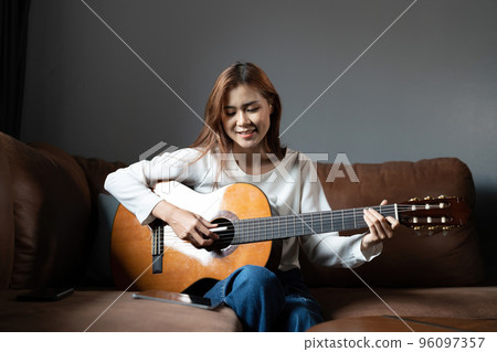 Image of happy beautiful woman playing guitar and composing song 96097357
