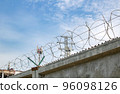 view of a high concrete fence with barbed wire at the top 96098126