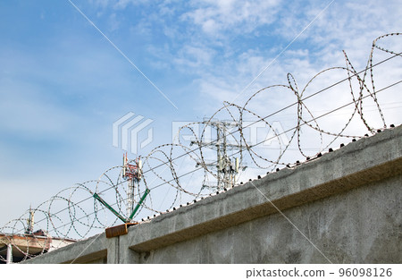 view of a high concrete fence with barbed wire at the top 96098126