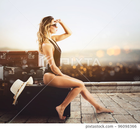 Young woman sitting on luggage waiting to go for a vacation 96098366