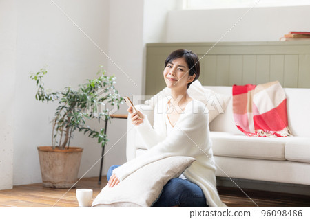 一個女人坐在客廳的地板上,看著她的智能手機 一個女人坐在客廳的地板上,看著她的智能手機 96098486