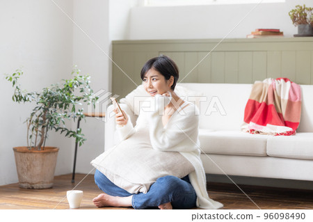 一個女人坐在客廳的地板上,看著她的智能手機 一個女人坐在客廳的地板上,看著她的智能手機 96098490