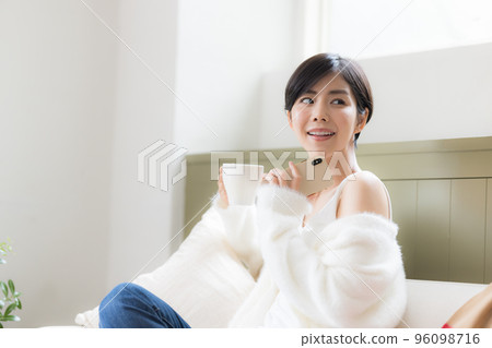 Portrait of a woman sitting on a sofa and looking at her smartphone Portrait of a woman sitting on a sofa and looking at her smartphone 96098716
