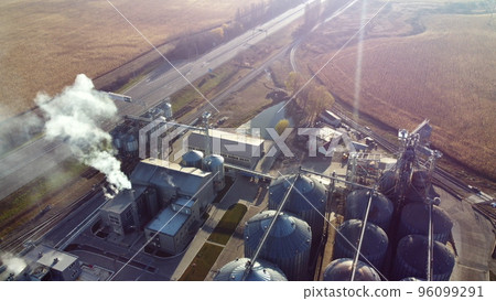 Aerial Drone View Flight Over complex of grain elevator buildings. Metal Round Silos and Metal Barrels for Grain Storage. Drying Storage Harvest. Elevator Tanks and Grain-drying complex. Large Granary Aerial Drone View Flight Over complex of grain elevator buildings. Metal Round Silos and Metal Barrels for Grain Storage. Drying Storage Harvest. Elevator Tanks and Grain-drying complex. Large Granary 96099291