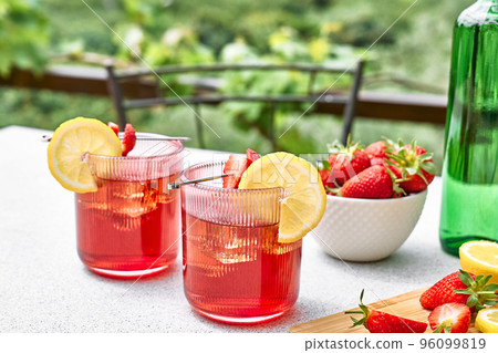Fresh summer strawberry cocktail or mocktail on the table in the garden. Sparkling pink strawberry lemonade. Fresh summer strawberry cocktail or mocktail on the table in the garden. Sparkling pink strawberry lemonade. 96099819