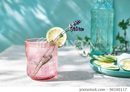 Cool lavender lemonade with lime slices and lavender flower on the table near pastel light blue background. Healthy organic summer soda drink. Detox water. Diet unalcolic coctail. Cool lavender lemonade with lime slices and lavender flower on the table near pastel light blue background. Healthy organic summer soda drink. Detox water. Diet unalcolic coctail. 96100117