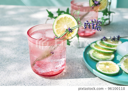 Cool lavender lemonade with lime slices and lavender flower on the table near pastel light blue background. Healthy organic summer soda drink. Detox water. Diet unalcolic coctail. Cool lavender lemonade with lime slices and lavender flower on the table near pastel light blue background. Healthy organic summer soda drink. Detox water. Diet unalcolic coctail. 96100118