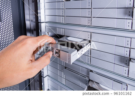 hand of a technician exchanging hard drive with SAS interface inside data center 96101162