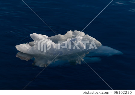 Big piece of ice in deep blue water 96102250
