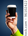Male hand holds, raised black paper cup of tea or coffee. 96102422