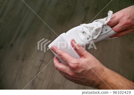 A man cleans white sneakers with  melamine sponge. 96102429