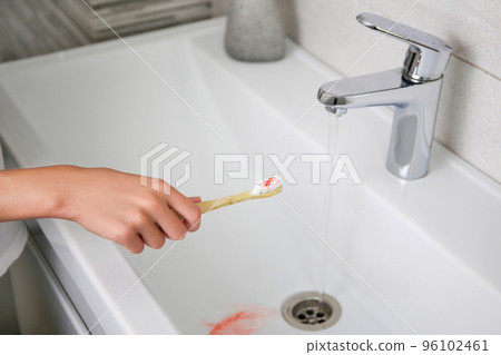 Blood on toothbrush on background of sink. Selective focus on the toothbrush. 96102461