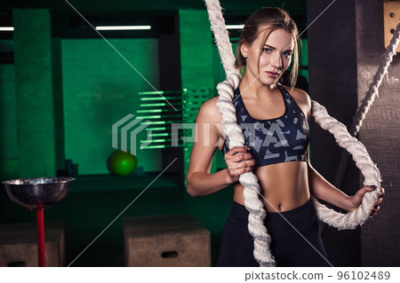 Shot of an attractive female crossfit athlete with a rope at the gym. 96102489