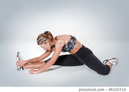 Stretching workout posture by a woman on studio gray background 96102510