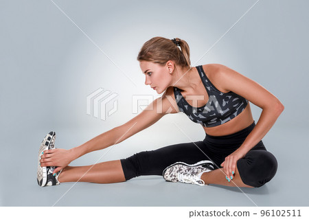 Stretching workout posture by a woman on studio gray background 96102511