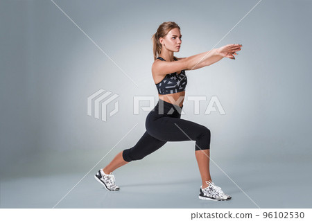 Stretching workout posture by a woman on studio gray background 96102530
