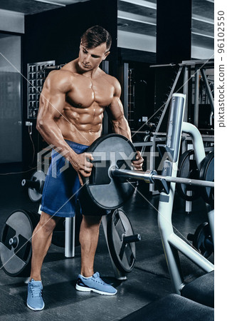 Portrait of a handsome man resting near bar in fitness gym and looking aside 96102550