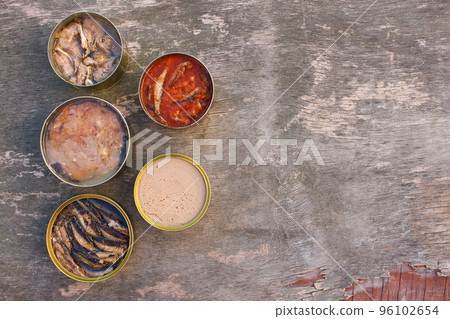 Different open canned food on old wooden background. Top view. Flat lay. 96102654