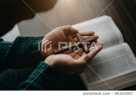 Close up of an open bible with a cross for morning devotion on a wooden table with window lights. 96103007
