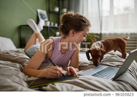 Girl drawing on graphic tablet in bed 96103823