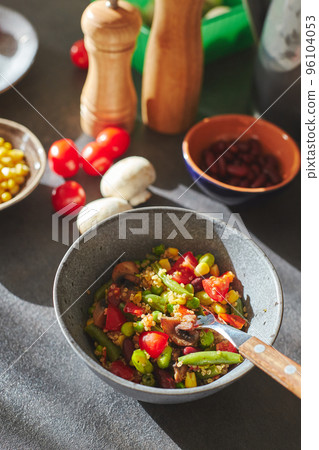 Sunliht modern kitchen with plate of quinoa filled with vegetables and ingredients on the countertop. Sunliht modern kitchen with plate of quinoa filled with vegetables and ingredients on the countertop. 96104053