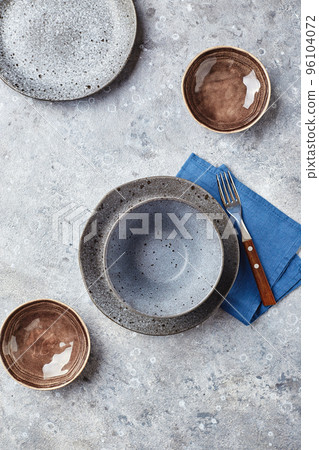 Empty gray bowl and plates on napkin on table 96104072