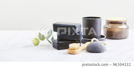 Three pieces of black charcoal soap, Konjac sponge, beauty care products, candles and brushes for washing and massage on marble background Three pieces of black charcoal soap, Konjac sponge, beauty care products, candles and brushes for washing and massage on marble background 96104322
