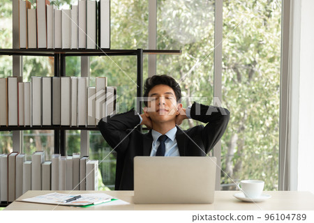 Young businessman relaxing at his work desk at office.. Young businessman relaxing at his work desk at office.. 96104789