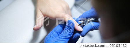 Cuticle for milling female nails. Manicurist girl uses scissors 96105482