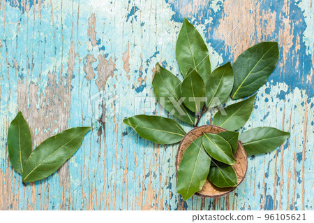 Fresh leaves of bay leaves in a bowl and beautifully laid out on a wooden rustic table. Top view Fresh leaves of bay leaves in a bowl and beautifully laid out on a wooden rustic table. Top view 96105621