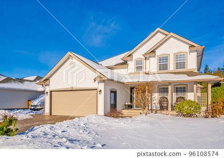 Family house with driveway and front yard in snow on winter sunny day 96108574
