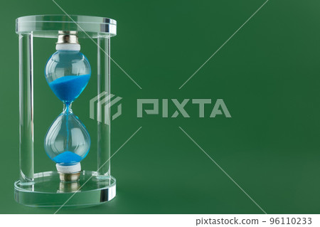 Sand hourglass on dark green paper background Sand hourglass on dark green paper background 96110233