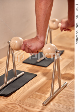 Man doing a handstand push-up using floor bars balancing on his hands. Fitness concept 96110891