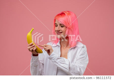 Joyous pink-haired girl pretending to call on a fruit phone 96111372