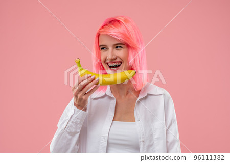 Girl posing with fresh yellow fruit against the pink background Girl posing with fresh yellow fruit against the pink background 96111382