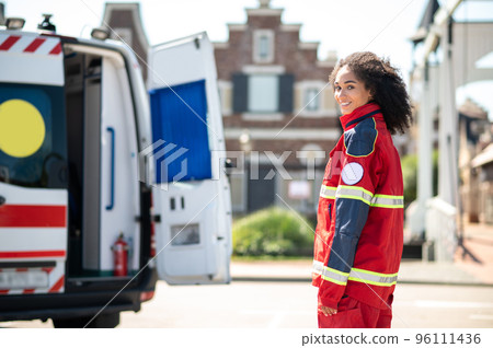 Cheerful emergency doctor posing for the camera beside the ambulance 96111436
